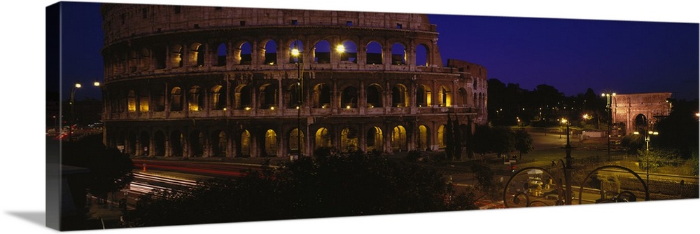 Wide angle photograph of the Coliseum, lit up at night, in Rome, Italy.