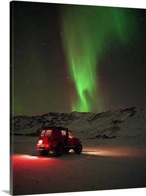 Jeep in a snow covered field with Aurora Borealis in the sky