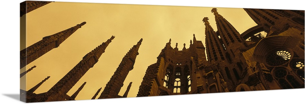 A wide angle photograph is taken from the ground and looking up toward the top of the Sagrada Familia church.