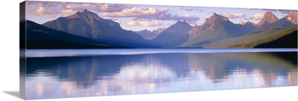 Oversized, horizontal photograph of mountains reflecting in the calm waters of Lake McDonald in Glacier National Park, Mon...