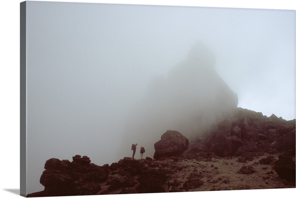 Lava tower in heavy fog, silhouetted hikers, Mount Kilimanjaro, Tanzania.