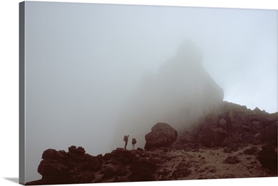 Lava tower in heavy fog, silhouetted hikers, Mount Kilimanjaro, Tanzania.