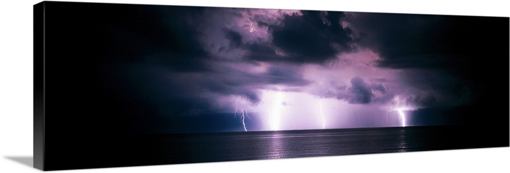 Panoramic photograph of a dark, stormy sky, several bright lightening bolts striking the horizon and reflecting in the wat...