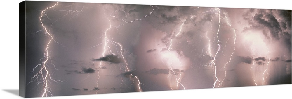 Panoramic canvas of lightning strikes up close against a stormy lit up sky.