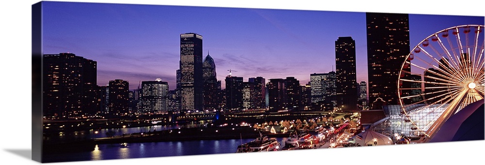 Panoramic photograph taken of a brightly lit skyline within a lively city in the Midwestern United States as the sun begin...