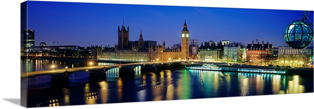 Panoramic photograph showcases the capital of the United Kingdom at dusk.  The colorful lights of famous landmarks includi...
