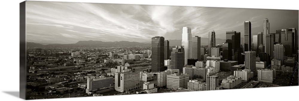 Panoramic photograph of Los Angeles, CA skyline with mountains in the distance and clouds overhead.