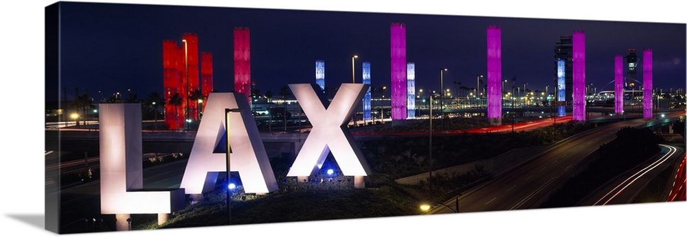 Large panoramic photograph of the Los Angeles International Airport with large LAX letters by a highway.