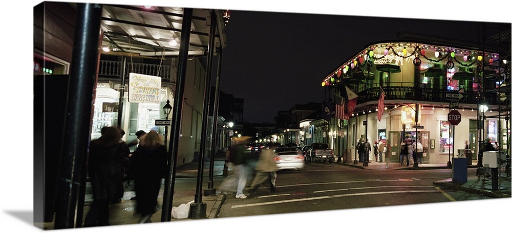 Picture taken of a street in New Orleans with buildings lit up and people walking along the sides.
