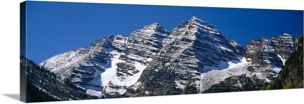 Panoramic photo on canvas of rugged mountains with snow on them.