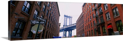 Low angle view of a suspension bridge viewed through buildings, Manhattan Bridge, Brooklyn, New York City, New York State