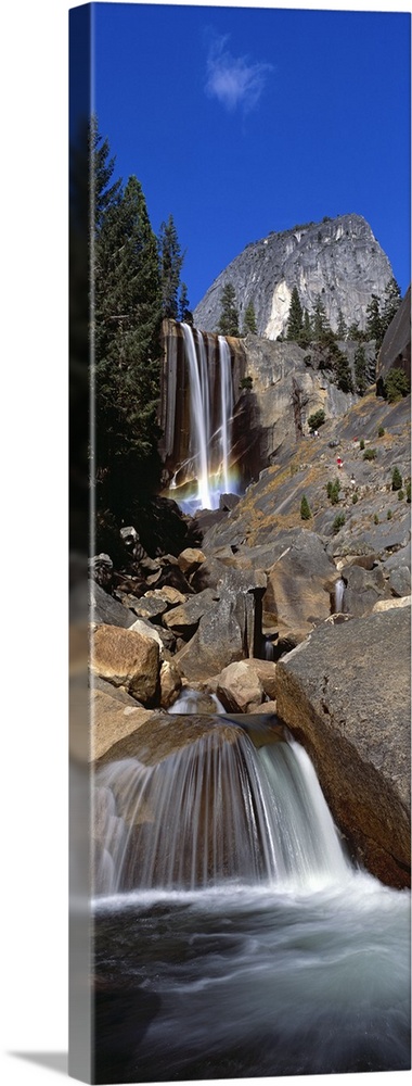 This picture is taken from below and looking up toward the top of a waterfall that flows over large rocks.