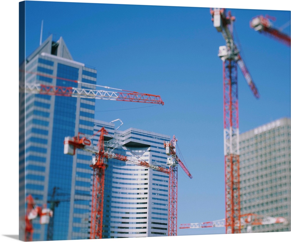 Low angle view of cranes in front of buildings