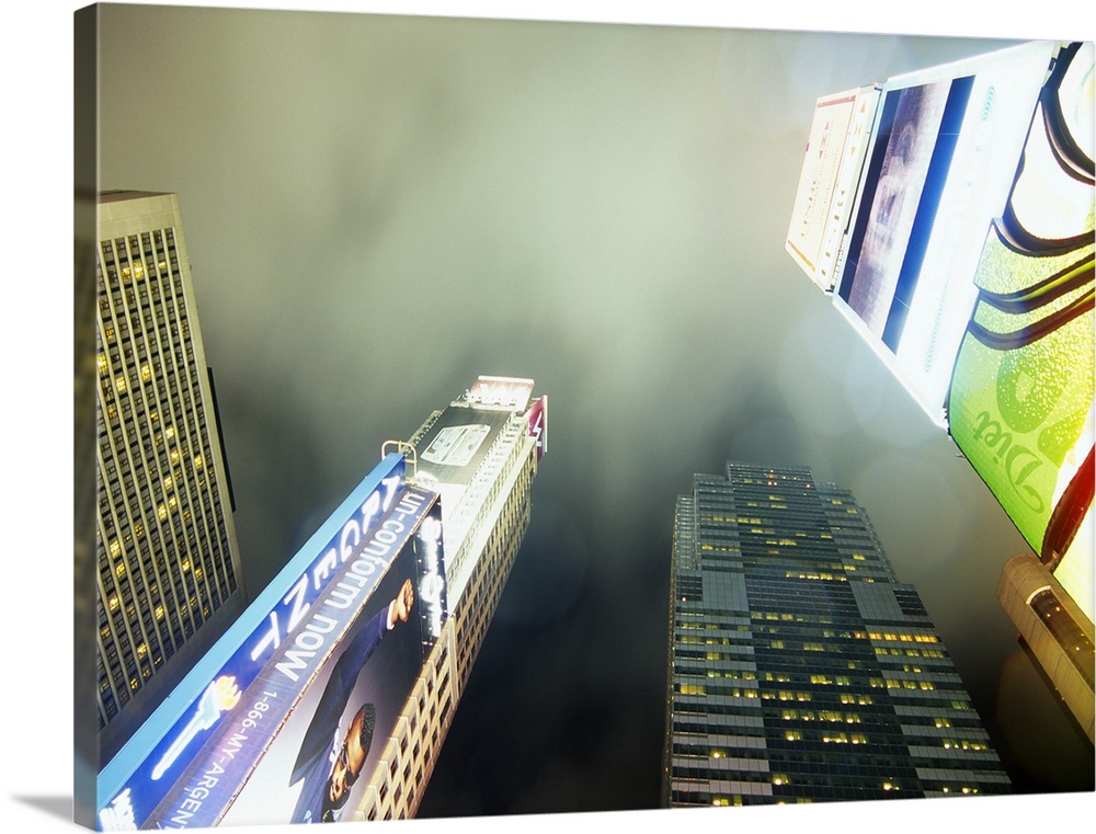 Oversized, landscape photograph from a low angle of several skyscrapers and lit advertising signs in Times Square, New Yor...