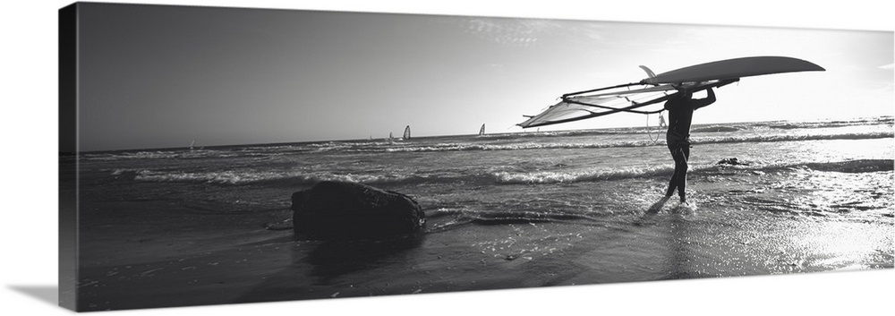 Man carrying a surfboard over his head on the beach, Santa Cruz, California