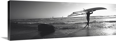 Man carrying a surfboard over his head on the beach, Santa Cruz, California