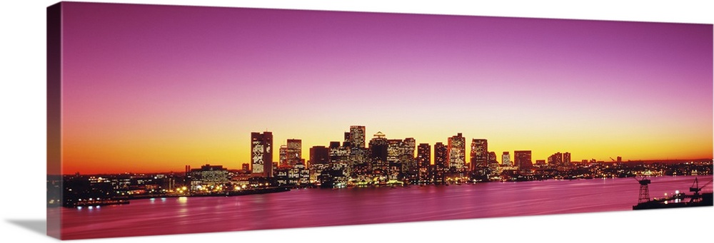 Big, wide angle photograph of a distant Boston skyline, with lit skyscrapers at sunset.