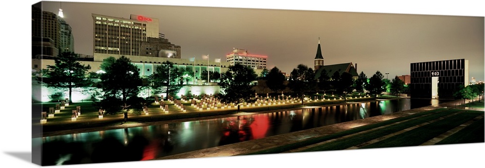 Panoramic photograph of skyline and waterfront at nigh.  The building lights are reflected in the water below.