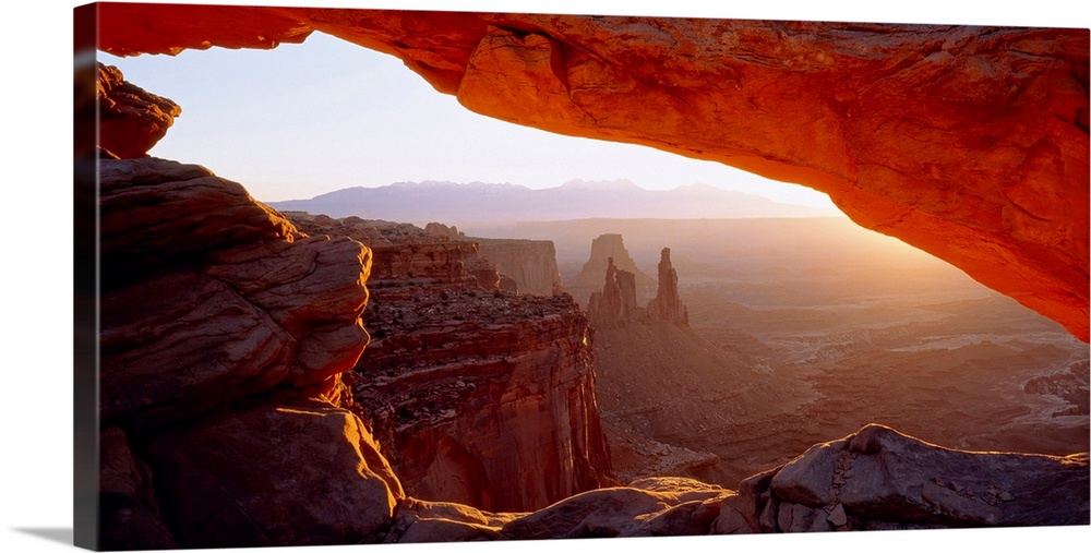 Wall art for the home or office this big picture shows a view of the desert at sunrise through a rocky arch.