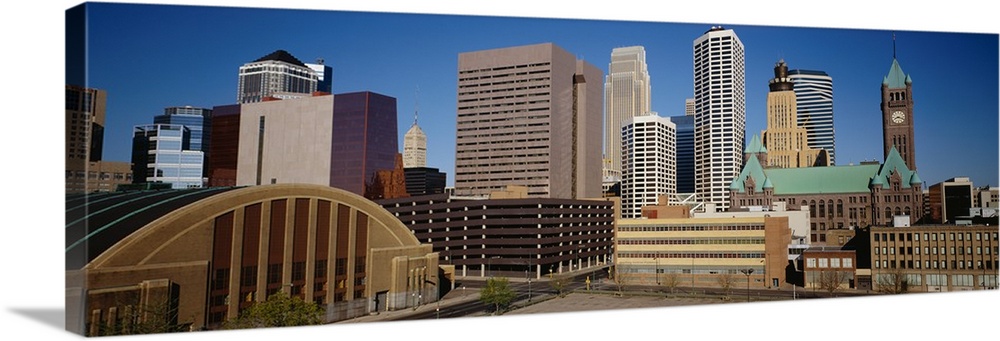 Big, panoramic photograph of the Minneapolis skyline against a blue, afternoon sky.