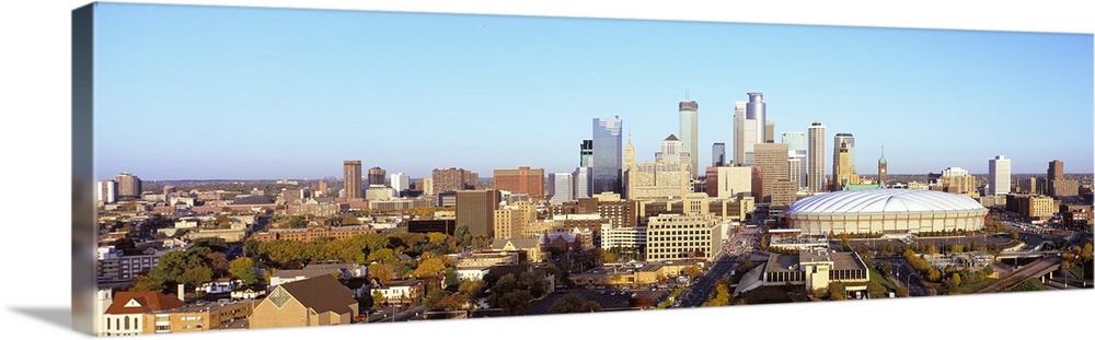 Oversized, horizontal photograph of downtown Minneapolis, Minnesota, beneath a light blue sky.