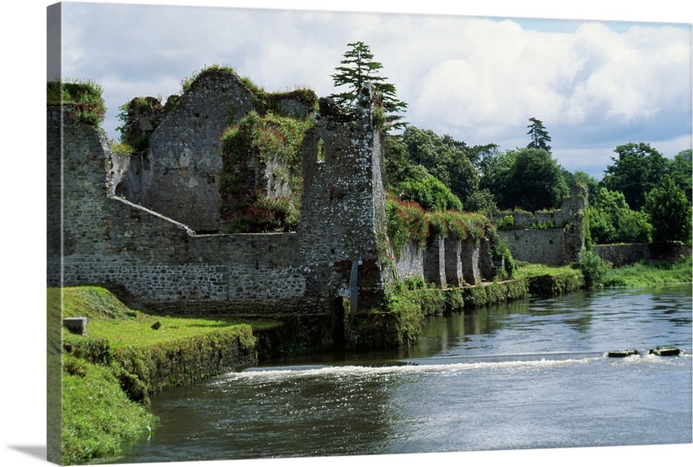 Photograph of grass covered stone castle ruins in Ireland with a moat surrounding the castle walls.
