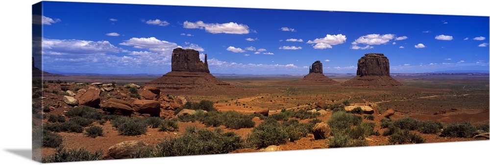 Panoramic photo on canvas of three tall rock formations in the desert under a bright blue sky.