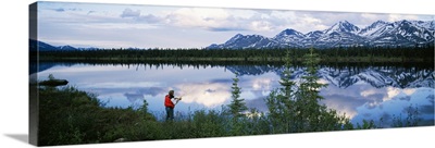 Mountain scene with lake reflection, fisherman at water's edge, spring, Alaska Range, Alaska