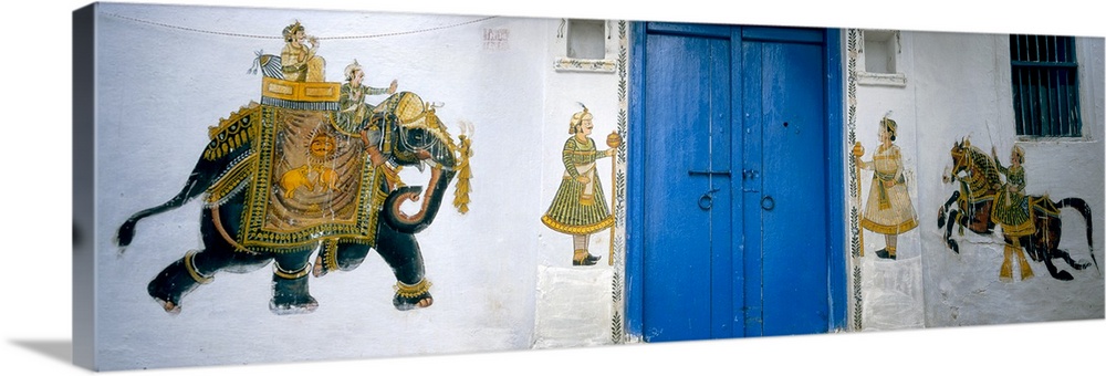 Panoramic photograph taken of a mural painted on either side of bright blue doors. The mural consists of a large elephant ...