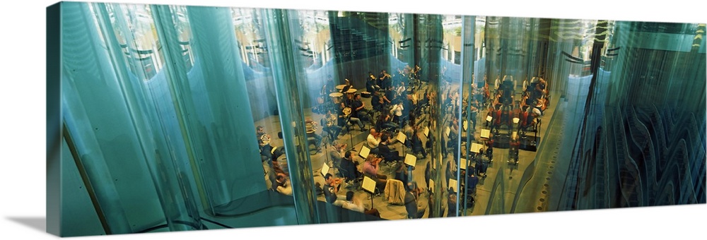 Photograph taken through a curvy glass design of musicians playing in a concert hall.