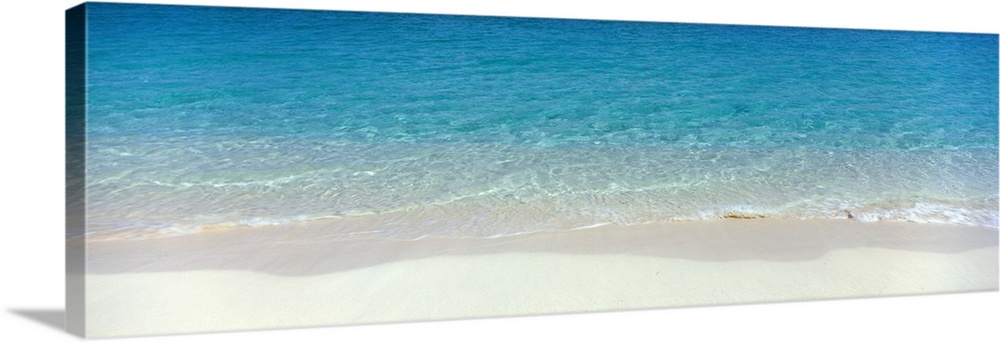 Panoramic photograph of shoreline with wet sand and crystal clear water.