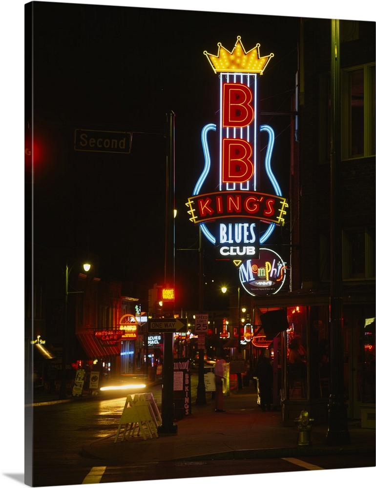 Vertical, large photograph of the street corner featuring the B.B. King's Blues Club neon sign, lit at night in Memphis, T...