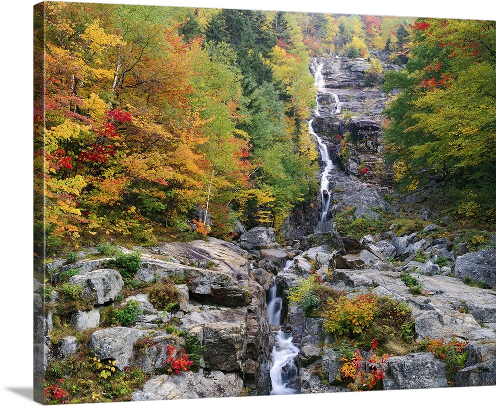 Photograph of waterfall surrounded by rocky terrain and a fall forest.