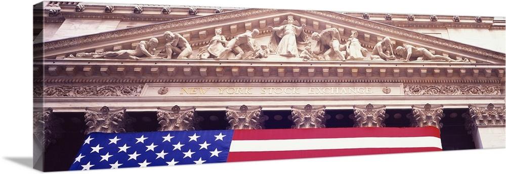 A panoramic photograph taken while looking up toward the top of the New York stock exchange. The American flag is hung fro...