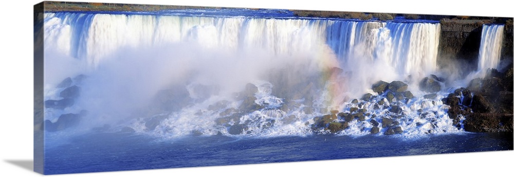 Panorama of the famous waterfalls in the Niagara Gorge. A rainbow forms in the mist created by the water splashing over th...