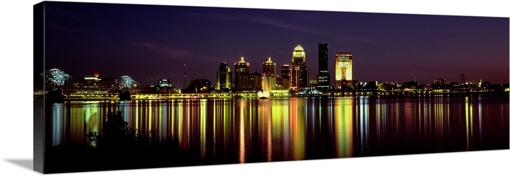 Panoramic photograph displays the radiantly shining skyline of the largest city in Kentucky at nighttime as it reflects ov...