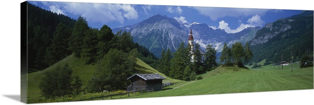 Large canvas print of rugged mountains in the background of a countryside field with a barn, fence and a tall tower.
