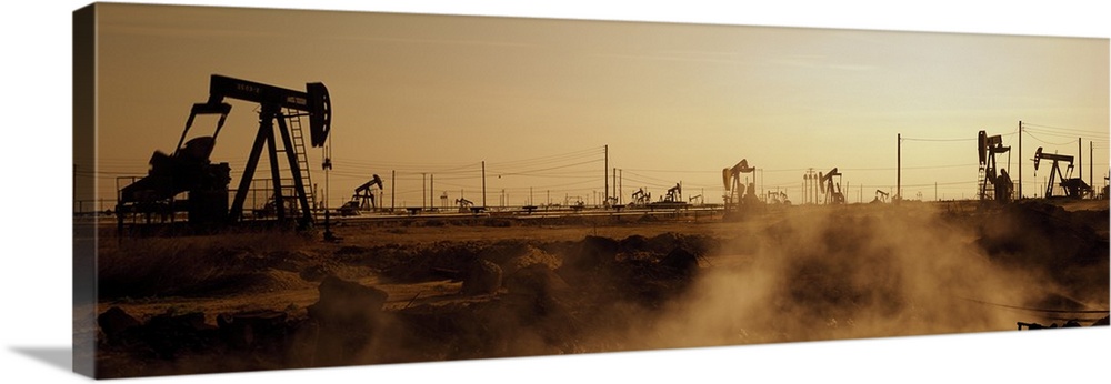 Panoramic photograph of many oil drills in a vast filed at sunset in Maricopa, Kern County, California.