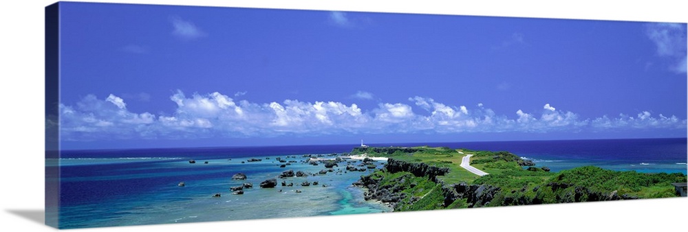 Panoramic photograph of peninsula stretching into ocean under a cloudy sky.