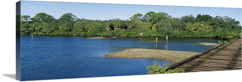 Old railroad trestle across a shallow bay at low tide showing oyster beds, Nokomis, Sarasota County, Florida,