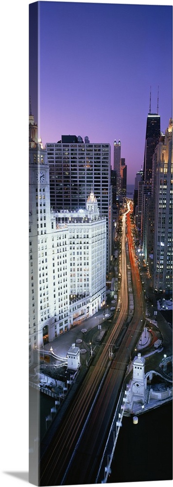 A photograph of a busy street going through downtown Chicago at night with the lights of the cars shown as streaks.
