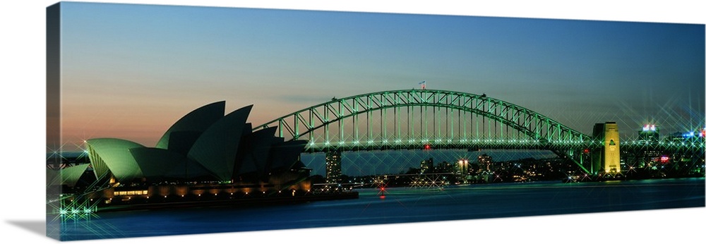 Long horizontal canvas of the Opera House in Sydney lit up at dusk with a bridge running behind it.