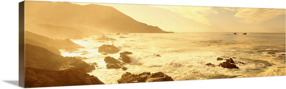 Wide angle photograph on a big canvas of the Pacific Ocean along a rocky coast line in California, as the sun rises, casti...