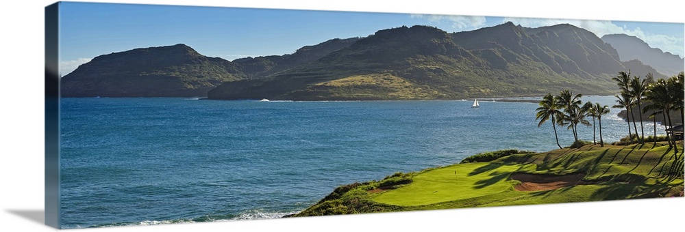 Panoramic photograph taken from a golf course of a large mountain across a lagoon in Hawaii.
