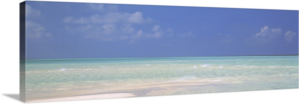 Panoramic canvas photo of a clear ocean meeting a sandy beach.