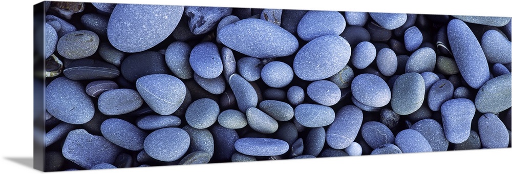 Close up horizontal photograph of smooth pebbles in various sizes, on Sandymouth Beach in Cornwall, England.