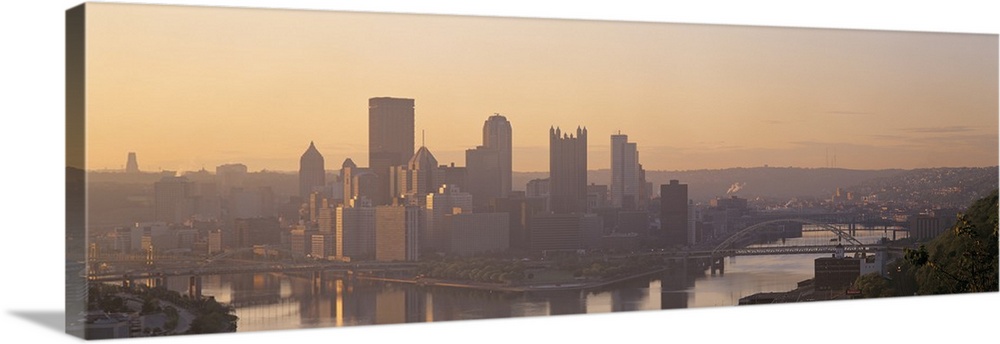 This is a panoramic photograph of the city skyline between two rivers becoming silhouetted in the late afternoon light.
