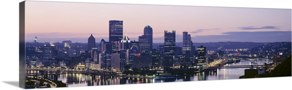 Panoramic photograph of skyline and waterfront lit up at sunset.