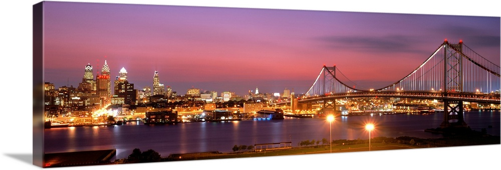 Oversized panoramic artwork of a night time photograph of the Benjamin Franklin Bridge leading to downtown.