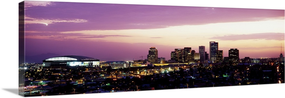 Panoramic photograph of city skyline lit up at sunset.